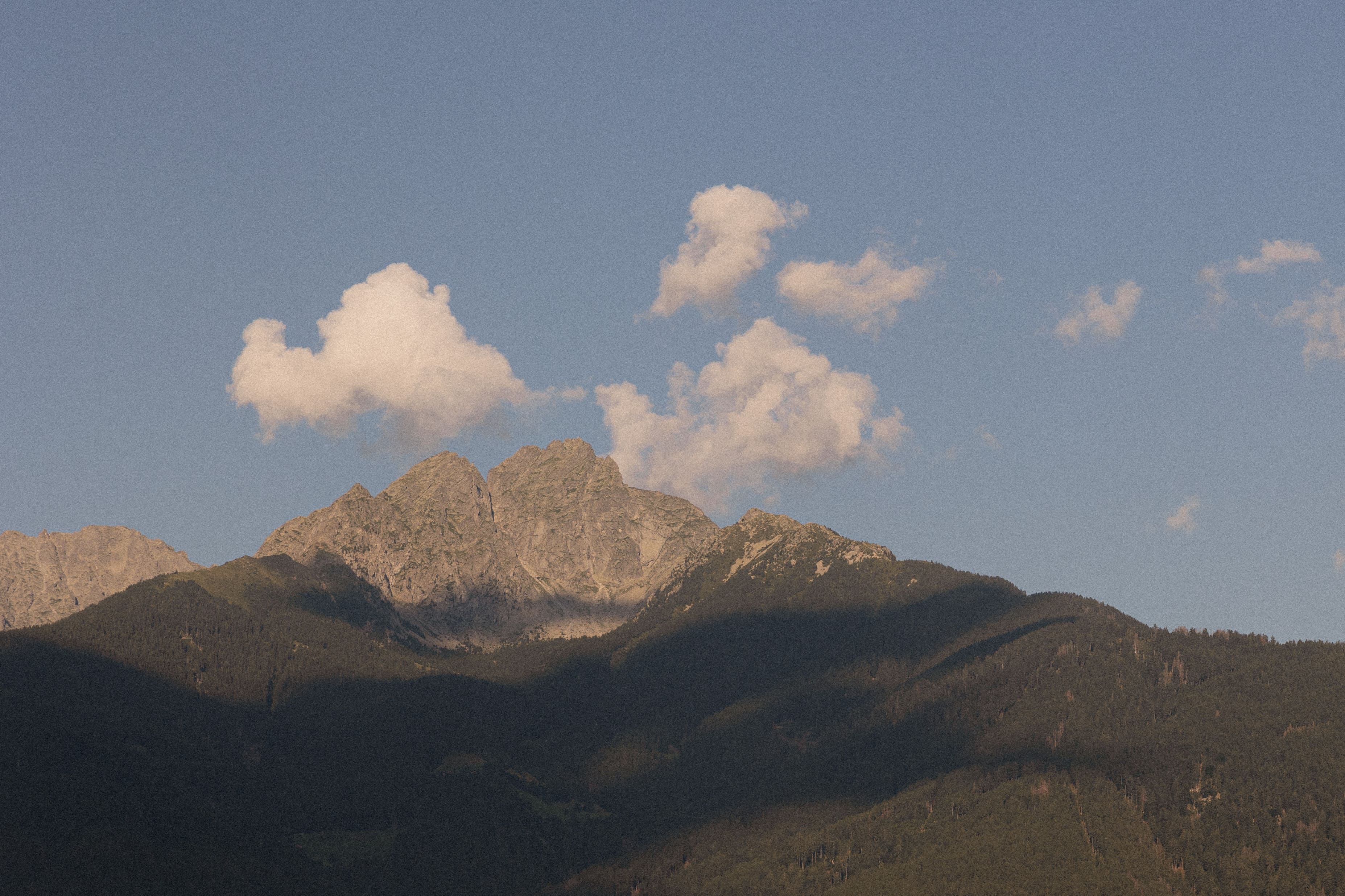 Bergkette unter klarem Himmel mit einigen Wolken, was auf Spätsommer oder frühen Herbst hinweist.